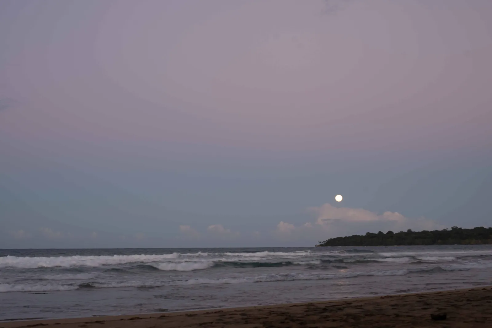 The moon rising over the Caribbean surf at dusk near Puerto Viejo