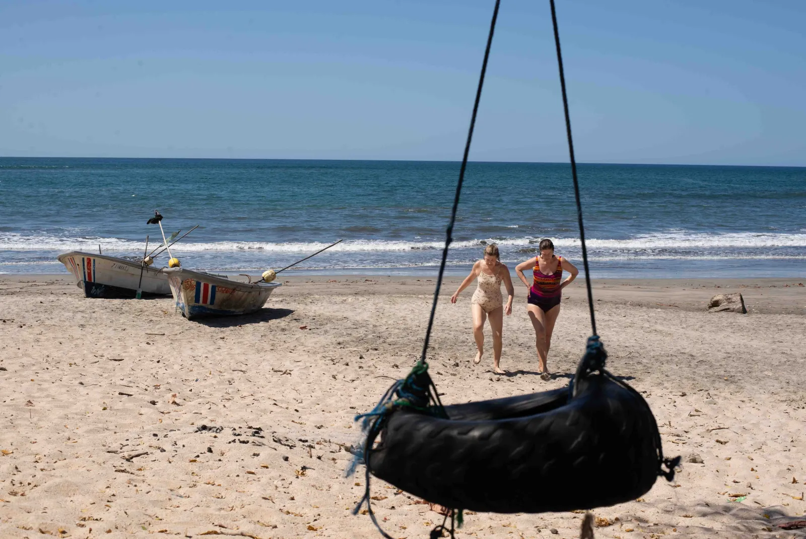 A tyre swing and beached boat on the wide sand at Santa Teresa